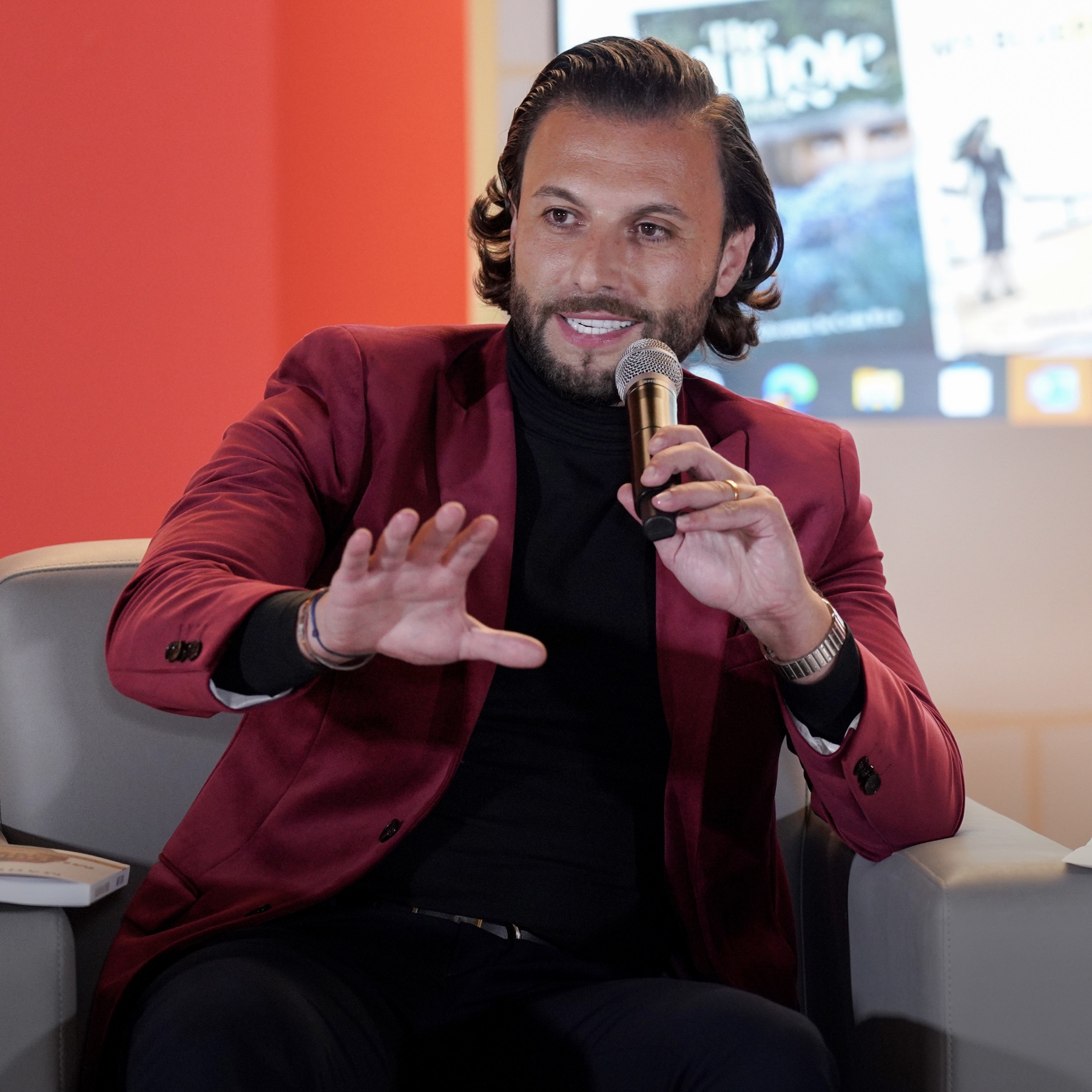 Maher Elusini speaking with a handheld microphone